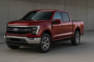 2025 Ford F-150 in metallic red parked in an industrial outdoor setting showcasing its bold grille, LED headlights, and muscular body profile.